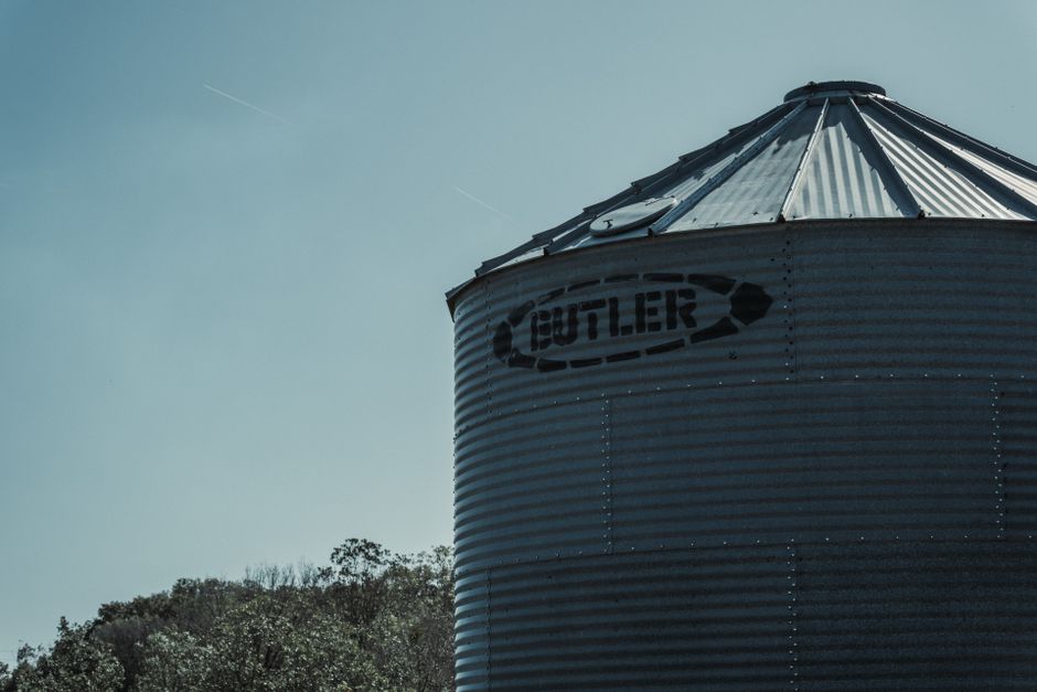 Grain bins and a farm equipment yard along a rural Iowa highway
