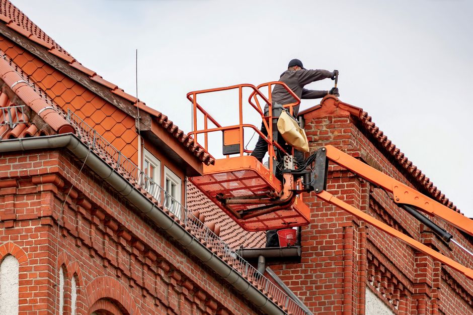 Ladder and rollforming equipment set up along a home's roofline during gutter work