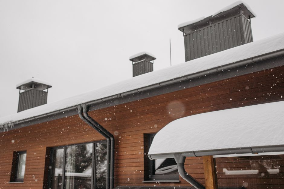 Weathered wood fascia board along a roofline where a gutter is mounted